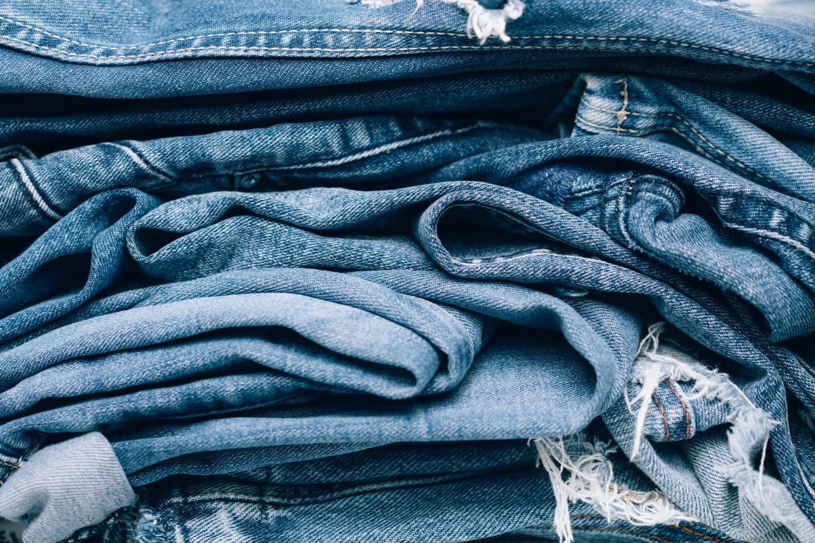 A closeup shot of a pile of denim material. Denim insulation, made from recycled cotton fibers, is non-toxic and hypoallergenic, making it a safe option for indoor use.