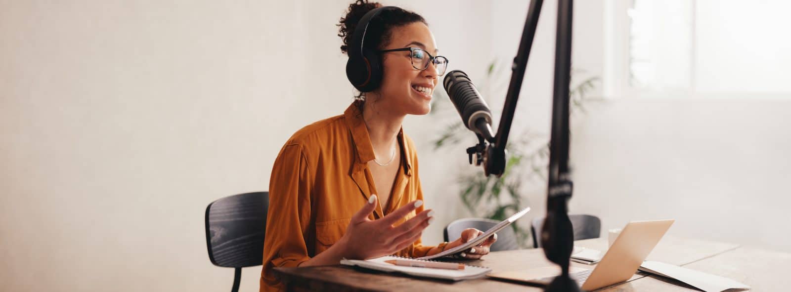 A women with headphones peaking in to a microphone to record a podcast
